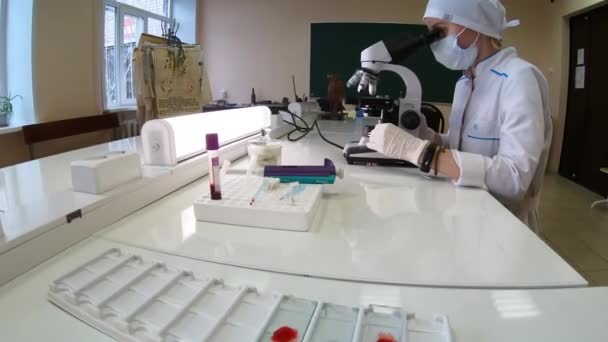 Een vrouwelijke arts doet medisch onderzoek met behulp van een microscoop. — Stockvideo