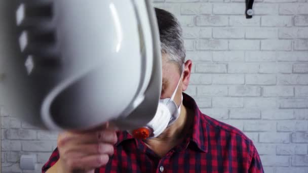 Retrato de un hombre con un casco de construcción y un respirador en la cara. — Vídeos de Stock