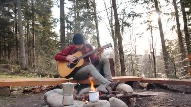 해군파란 모자를 쓰고 산불 이난 숲 속 관광객 이 기타를 연주하는 모습 — 비디오