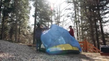 Genç kadın ve erkek yürüyüşçü ormanda kumaştan bir çadır kurdular..
