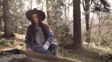 Ormandaki kız, bir bardak kaynak suyu alıp içiyor.