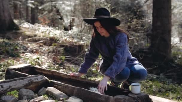 Flicka turist, sommar, i en hatt, i skogen, dricker källvatten från en brunn — Stockvideo