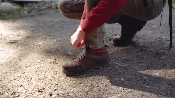Il tipo lega i lacci sugli stivali marroni in piedi su un ginocchio a terra. — Video Stock