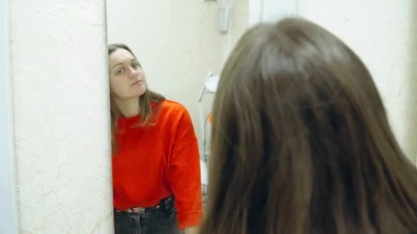 Młoda piękna dziewczyna patrzy na siebie w lustrze — Wideo stockowe