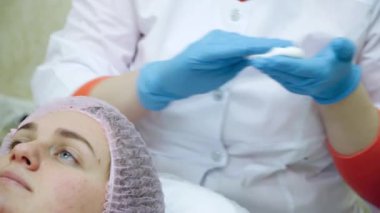 Kadın profesyonel yüz prosedürü yaptırıyor. Güzellik uzmanı yüzüne köpük sürer.