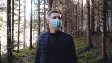 Adam dışarıda kameraya bakarken koruyucu maskesini çıkarıyor.