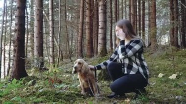 Ormanda maskeli bir kız ormanda köpeğini cocker spaniel ile okşuyor.