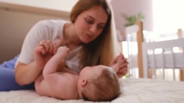 Authentic close up shot of young neo mother is playing with her newborn baby in a nursery in a morning. Shot in 8K. Concept of children,baby, parenthood, childhood, life, maternity, motherhood. 4k
