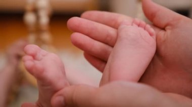 Close-up video of a mother, grandmother, woman or babysitter is cutting her little sons or boy nails with nail scissors, at home. care of the child. grey background. High quality 4k footage