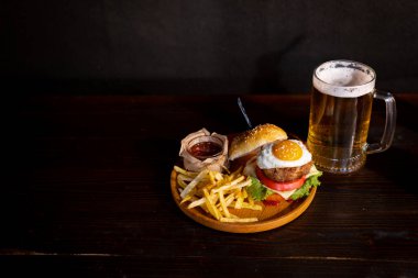 Hamburger. Sandwich with chicken burger, tomatoes, pickled cucumber and fried egg. Fresh tasty chicken burger on wooden table. beer. High quality photo