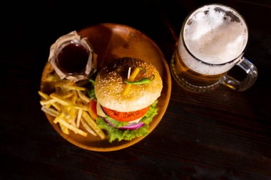 Hamburger. Sandwich with chicken burger, tomatoes, pickled cucumber and fried egg. Fresh tasty chicken burger on wooden table. beer. High quality photo