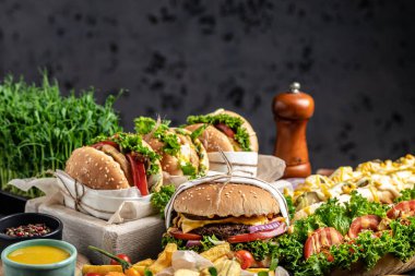 Tahta masada sosisli sandviç, hamburger ve patates kızartması. Fast food atıştırmalıkları. Fast food ve abur cubur kavramı.