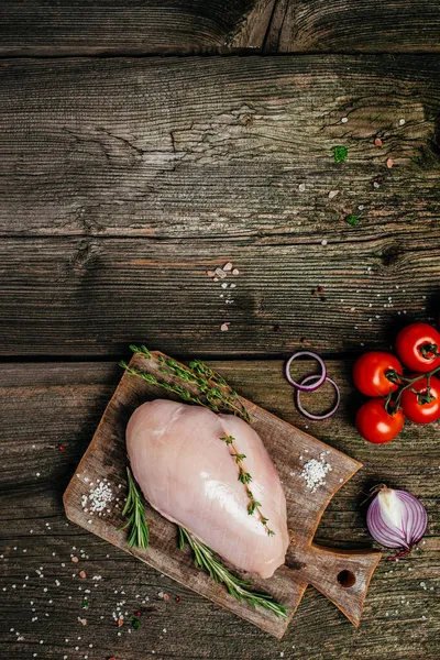 A piece of turkey fillet on a wooden chopping board, Cooking ingredients. vertical image. top view. place for text,