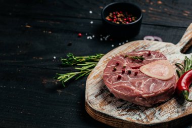 Çiğ sığır eti osso buco biftek, otlar ve baharatlar ile koyu arka planda. afiş, menü, metin için tarif yeri, üst görünüm.