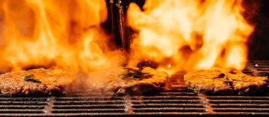 Barbekü ızgarasında çiğ biftek, kızgın kömürlerin üzerinde cızırdıyor. Çelik ızgara et burger. Uzun pankart biçimi.