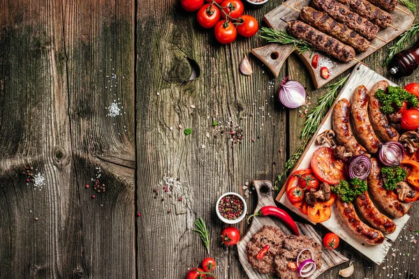 Various kinds of grilled gourmet meats on a rustic wooden table. Barbecue menu. banner, menu, recipe place for text, top view.