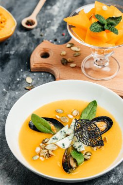 Deniz ürünleri, midye, karides, mavi peynir ve beyaz kasede küflü geleneksel balkabağı çorbası. dikey görüntü. en üstteki görünüm.