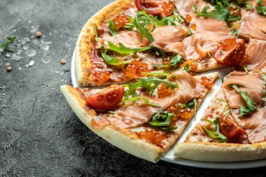 Somonlu lezzetli sıcak pizza, kırmızı havyar, domates ve aragula yemeye hazır. afiş, menü, metin için tarif yeri, üst görünüm.