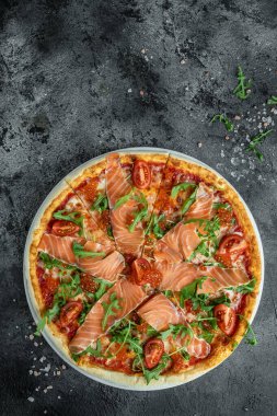 Somon füme pizza, kırmızı havyar, domates ve aragula yemeye hazır. İtalyan mutfağı. dikey görüntü. Üst Manzara. metin için yer.