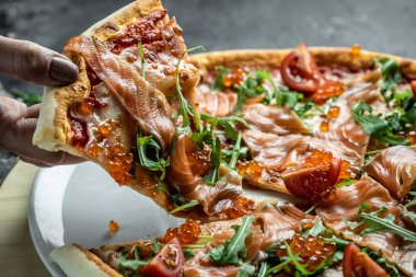 Kadın, somon, kırmızı havyar, domates ve aragüllü dilimlenmiş pizza. Geleneksel İtalyan mutfağı. Lezzetli kahvaltı ya da atıştırmalık.