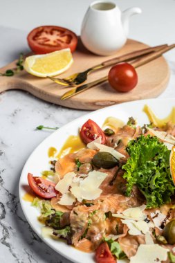 Kapari, parmesan ve vişneli domatesli somon carpaccio. Restoran menüsü, diyet, yemek kitabı tarifi. en üstteki görünüm.