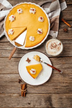 Krem şanti ve latteyle süslenmiş bir parça balkabaklı peynirli kek. dikey görüntü. Üst Manzara. metin için yer.