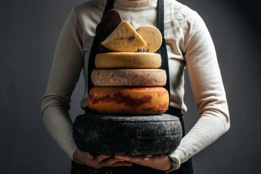 Peynir üreticisinin elinde bir kafa dolusu sert peynir. Farklı lezzetli süt ürünleri..