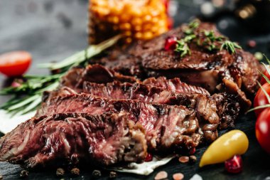 Mısır ve kiraz domatesli ızgara Biftek Siyah Angus. Dilimlenmiş orta pişmiş taze sulu lezzetli biftek ve koyu bir arka plan..