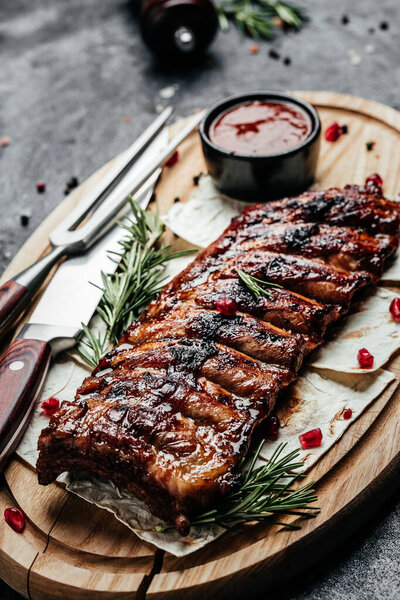 Pork ribs grilled with BBQ sauce. Tasty snack on wooden board. Food recipe background. Close up.