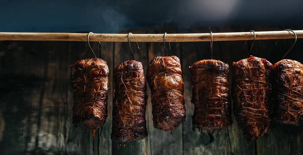 Composition of meats. Traditionally smoked ham. Hanging ham in the smokehouse smoked bacon for smoking. Long banner format.