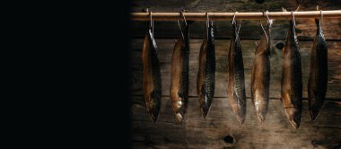 Uskumru balığı tütsüleme evinde tüttürdü. Tüttürme İşlemi Balığı. Sigara tiryakisinde yan yana asılı sigara içen balıklar. Uzun pankart biçimi.