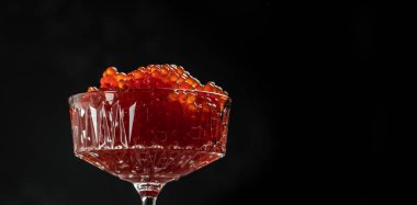 Siyah arka planda leziz kırmızı havyar. Gurme yemekleri yakın, aperatif, seçici odak, metin için yer,