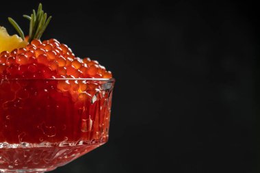 Bir kaşıkta kırmızı havyar. Siyah arka planda kase havyar. Yakın çekim somon havyar. Şarküteri. Gurme yemek. Havyar dokusu. Deniz ürünleri.