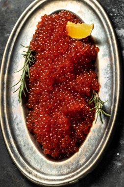 Metal tabakta kırmızı havyar ve arka planda bir bardak şampanya. Gurme yemekleri yakın, aperatif, seçici odak, metin için yer,