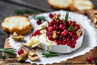 Taze biberiyeli, kızılcık soslu ve ahşap masada baget ekmekli nefis pişmiş camembert peyniri. Pankart, yemek servisi menü tarifi yeri, metin, üst görünüm.