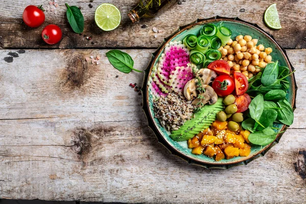 İçinde kinoa, avokado, mantar, salatalık, nohut, ıspanak, domates, avokado sebze salatası olan Buda Kasesi. Temiz beslenen vejetaryen gıda konsepti. en üstteki görünüm.