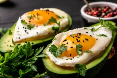 Kızarmış avokado yumurta tekneleri, taze roka, biber, düşük karbonhidratlı yüksek yağlı kahvaltı. en üstteki görünüm.