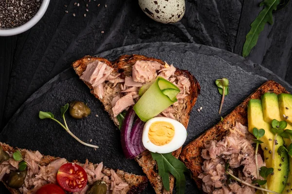 Kolekcja kanapek z tuńczykiem bruschetta. Pyszne śniadanie lub przekąska. Toasty z tuńczykiem pyszne zdrowe jedzenie na ciemnym tle, Widok z góry — Zdjęcie stockowe