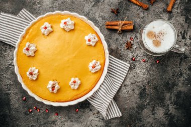 Traditional American pumpkin pie with cinnamon decorated with whipped cream and latte. banner, menu, recipe place for text, top view.