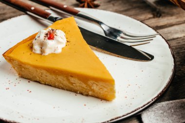 Plate with slices of pumpkin cheesecake with whipped cream, top view,