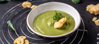 Bir kase brokoli krem çorbası, parmesan peyniri ve ahşap masanın üstünde çıtır çıtır çıtır ekmek..