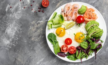 Ketojenik kahvaltı. Keto düşük karbonhidratlı somon, haşlanmış karides, karides, kızarmış yumurta, taze salata, domates, salatalık ve avokado. Üst Manzara. Düşük karbonhidrat diyeti. yüksek yağ diyeti.