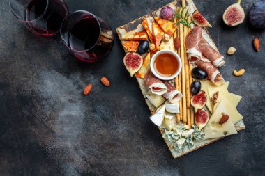 Appetizers table with italian antipasti snacks and wine in glasses. cheese, ham, nuts, fruit, bread sticks. Delicious balanced food concept. banner, menu, recipe place for text, top view.