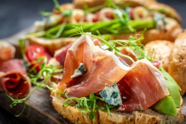 Çeşit çeşit aperatif Croissant sandviçi jamon jambonlu serrano paleta iberica, mavi peynir, avokado, mavi arka planda mikrocin. Lezzetli aperatifler, mezeler, tapalar..