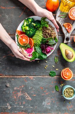 Kızların elleri Quinoa sebzeli vejetaryen Buda kâsesi avokado, kan portakalı, brokoli, karpuz turpu, ıspanak, kinoa, balkabağı çekirdeği. en üstteki görünüm.