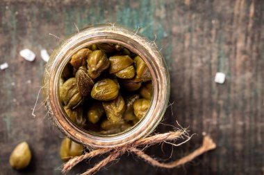 Turşu turşusu. Konserve kapari, sirkede tuzlanmış kapari ahşap zemin, pankart, metin için menü tarifi yeri, üst görünüm,