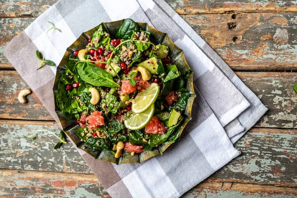 Vegan winter salad with quinoa, spinach, avocado, grapefruit, pomegranate, nuts and microgreens, Food recipe background. top view.