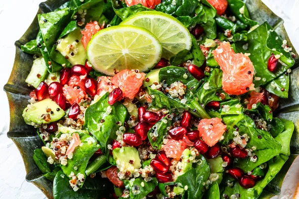Vegan winter salad with quinoa, spinach, avocado, grapefruit, pomegranate, nuts and microgreens, Food recipe background. top view.