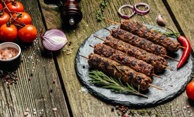 Sığır eti kıyma üzerinden bir çubuk üzerinde şiş kebap. Lula kebap, geleneksel Kafkas çanak. Ketçap ile bir kesme tahtası üzerinde betonun siyah arka plan üzerine alan yukarıdaki baharat ve domates kopyalama