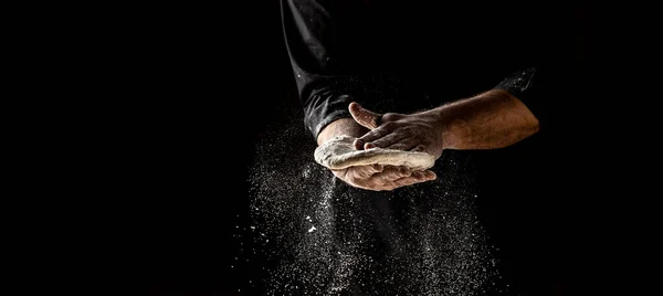 Clap hands of baker with flour. Beautiful and strong men\'s hands knead the dough make bread, pasta or pizza. Powdery flour flying into air.